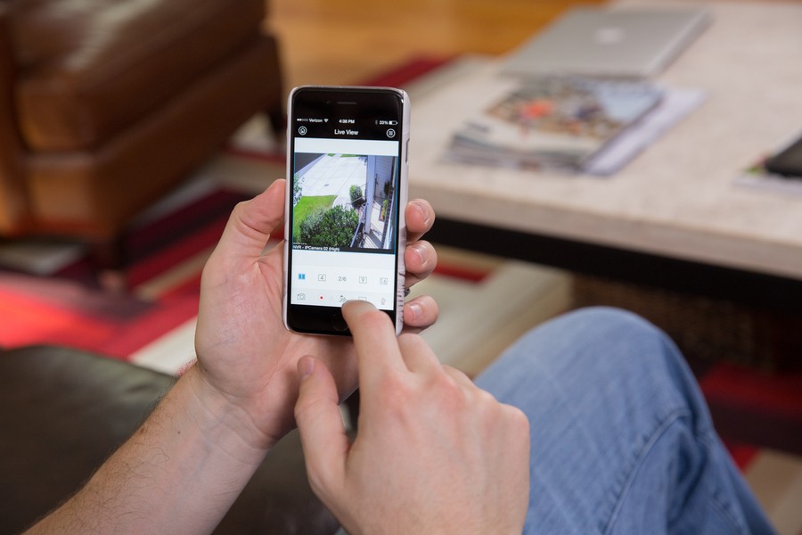 A man looks at a security camera video feed on his smartphone. 